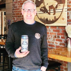 Upstate beer tourist holding a rusty nickel 36 ounces crowler.